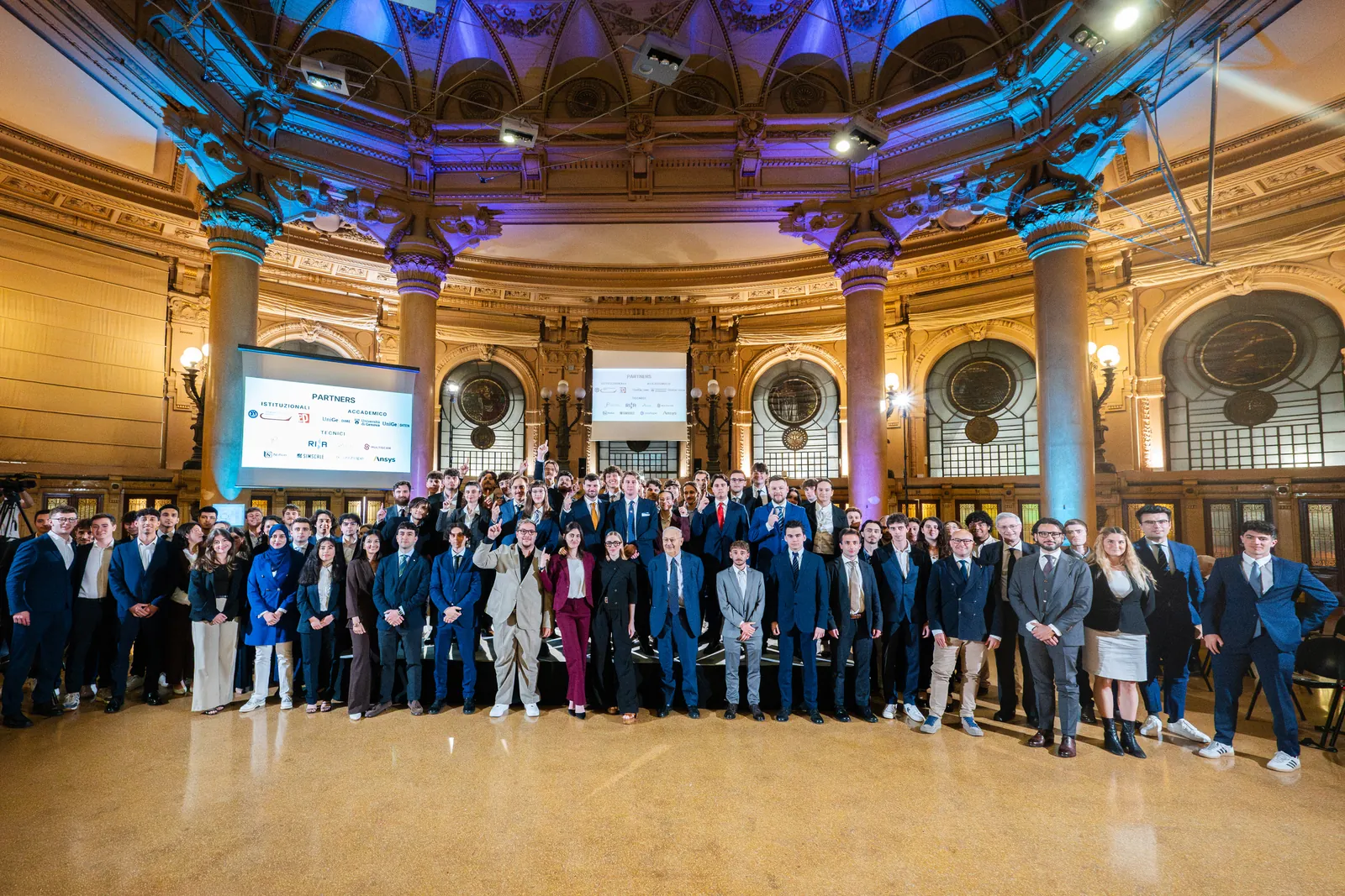 Rund hundert Menschen posieren im Saal des Palazzo della Borsa in Genua